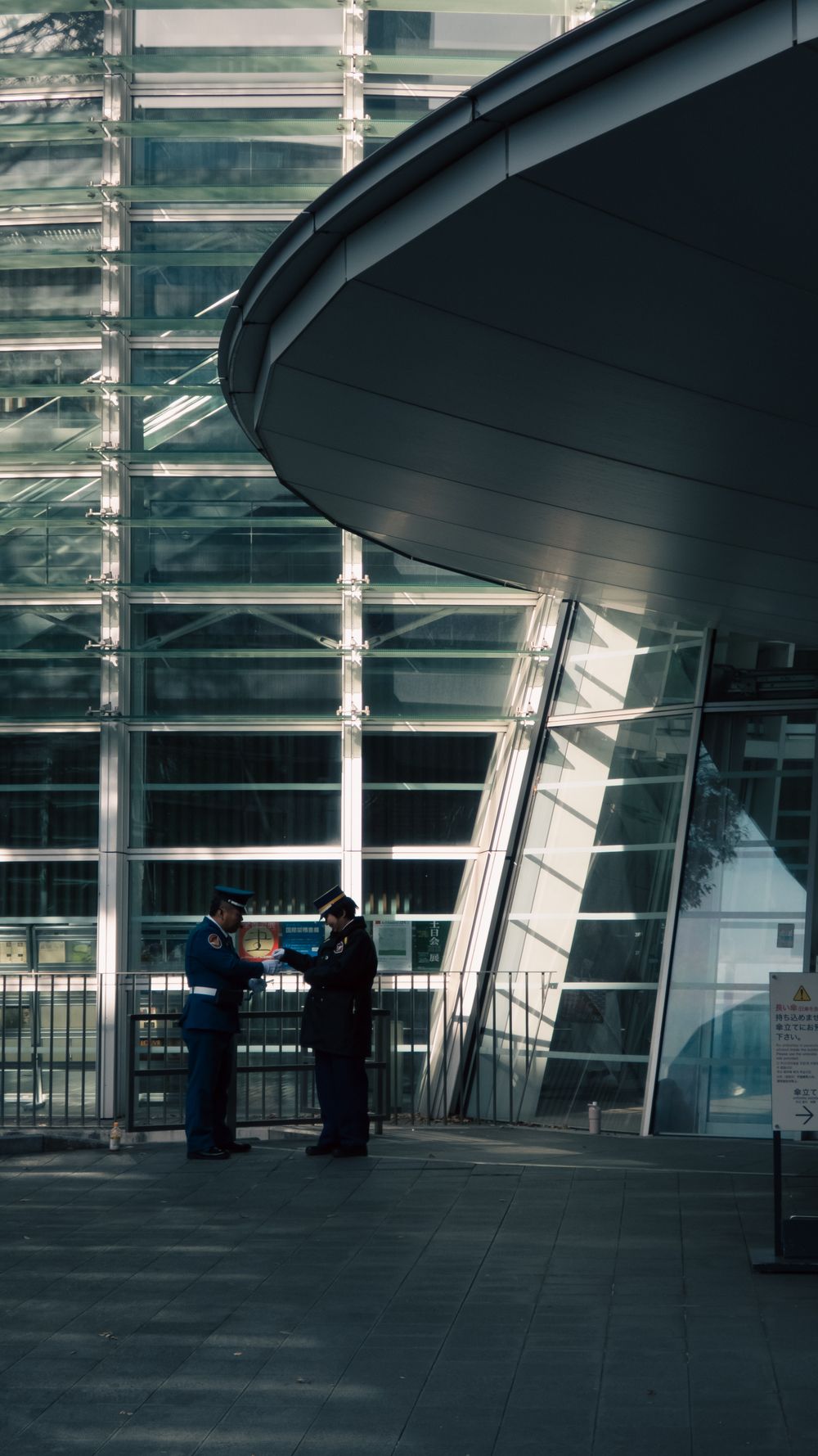 Two uniformed security officers reviewing a post order outside a commercial building